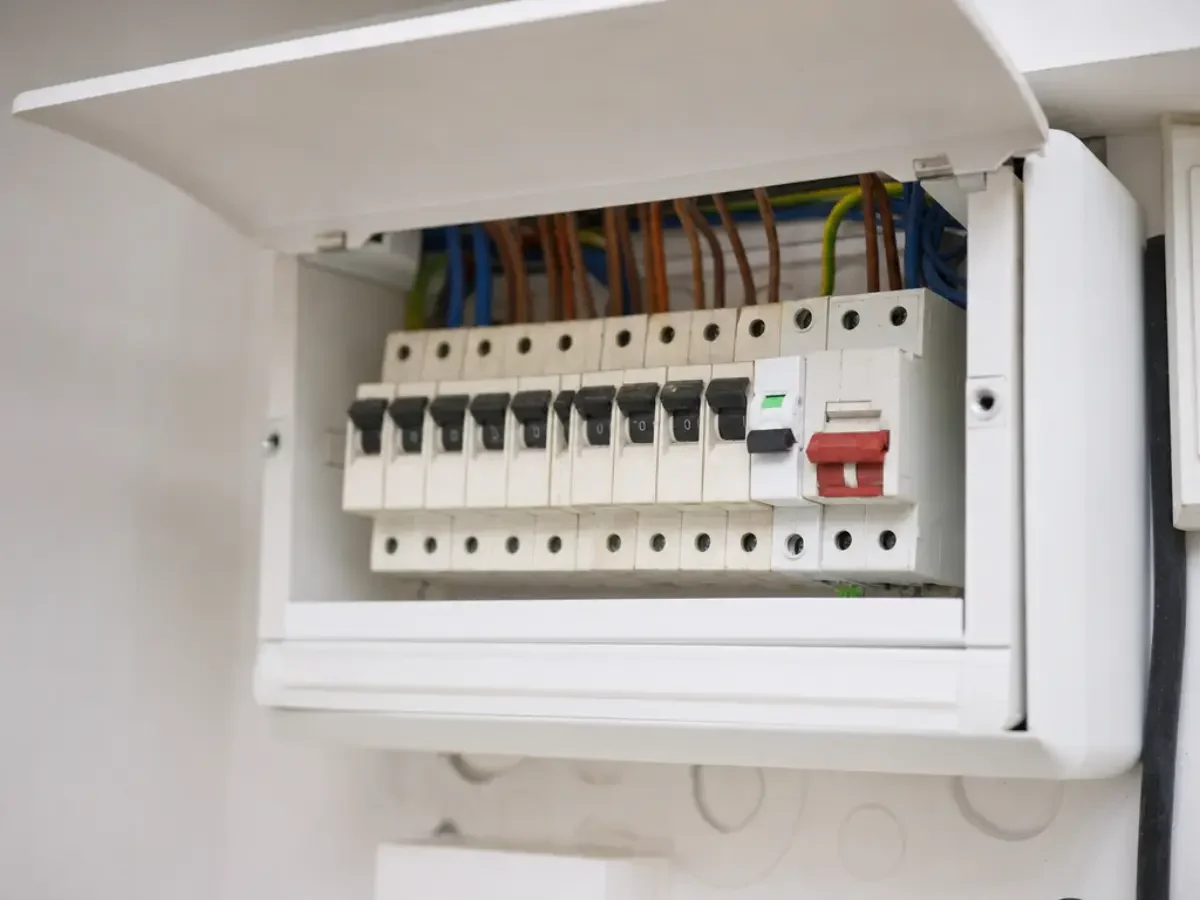 Illustration of an open consumer unit with one new breaker fitted among older ones by Re-energize Electrical