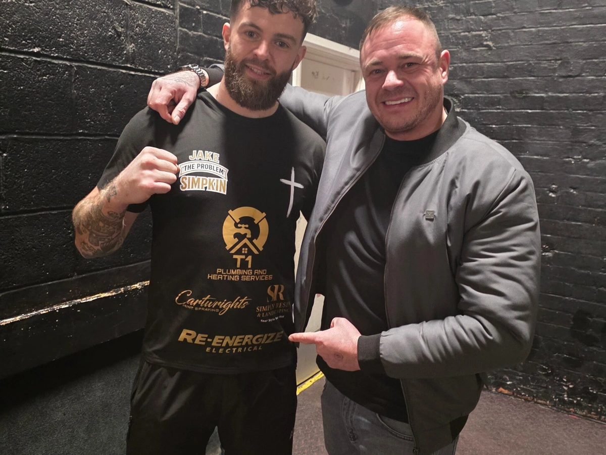 Jake Simpkin in his ring-walk t-shirt, with a supporter pointing to the Re-energize Electrical logo