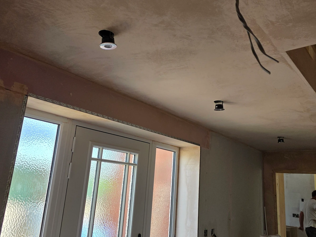 Downlights fitted in a newly plastered ceiling with a cable left ready for another fitting